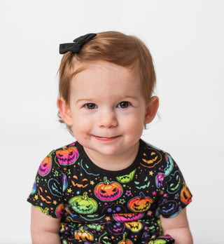 Girl wearing black bamboo clip on bow for babies and toddlers, and kids