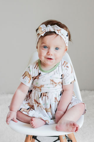 Baby girl wearing headband bow and bamboo bodysuit dress for babies and toddlers in Perfect Ponies print