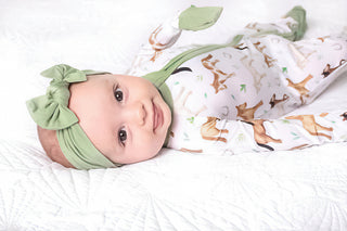 Baby girl wearing headband bow and bamboo zipper pajamas for babies and toddlers in Perfect Ponies print
