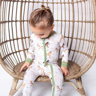 Boy wearing bamboo zipper pajamas for babies and toddlers in Perfect Ponies print