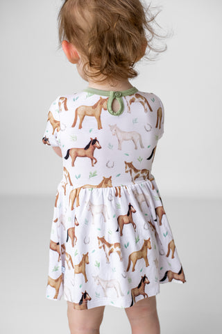 Girl wearing bamboo bodysuit dress for babies and toddlers in Perfect Ponies print