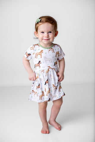 Girl wearing bamboo bodysuit dress for babies and toddlers in Perfect Ponies print