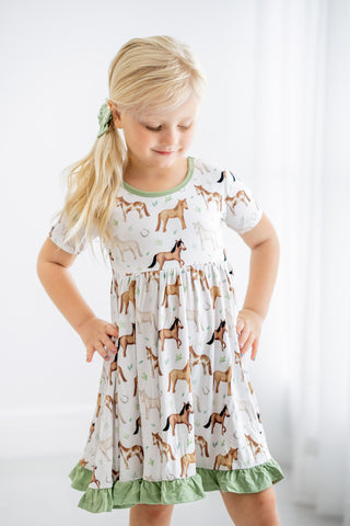 Girl wearing bamboo ruffle dress for toddlers and kids in Perfect Ponies print