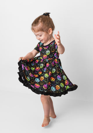 Girl twirling in bamboo ruffle dress for toddlers and kids in Halloween Pumpkins print